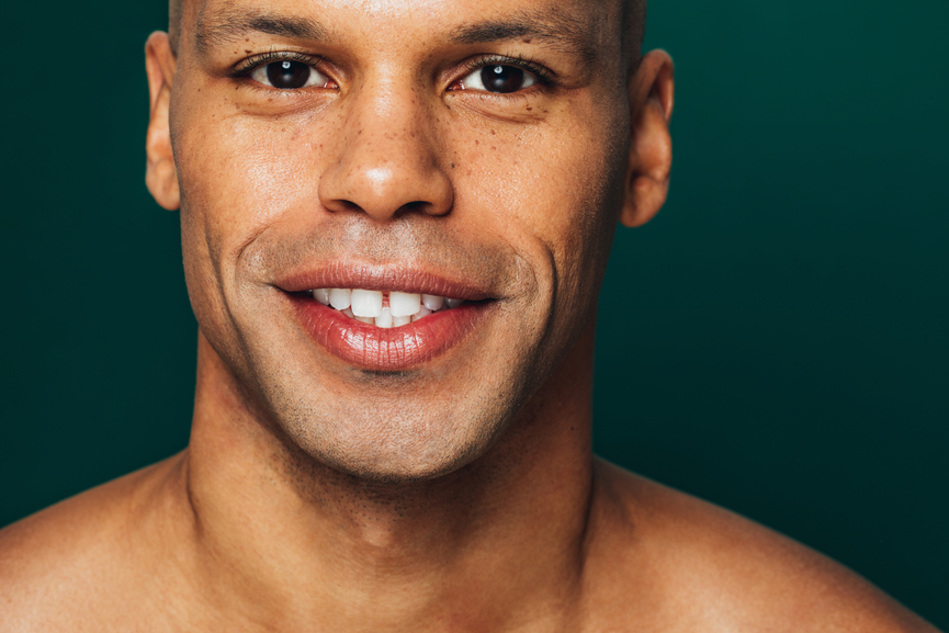 Close up of a cute mixed race man posing half naked in the studio in front of a green background